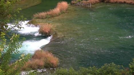 large volumes of water flowing from one pond down to another through grass in krka national park in croatia at ¼ speed