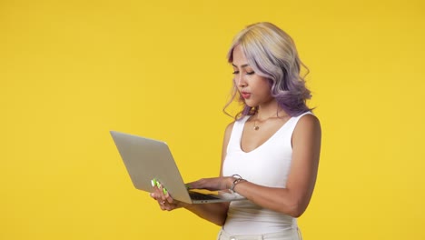 joven asiática usando una computadora portátil aislada sobre un fondo amarillo
