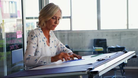 Female-architect-working-on-blueprint-over-drafting-table-4k