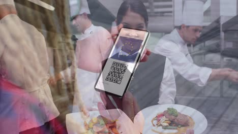 animation of woman holding smartphone with covid 19 vaccination passport over restaurant kitchen