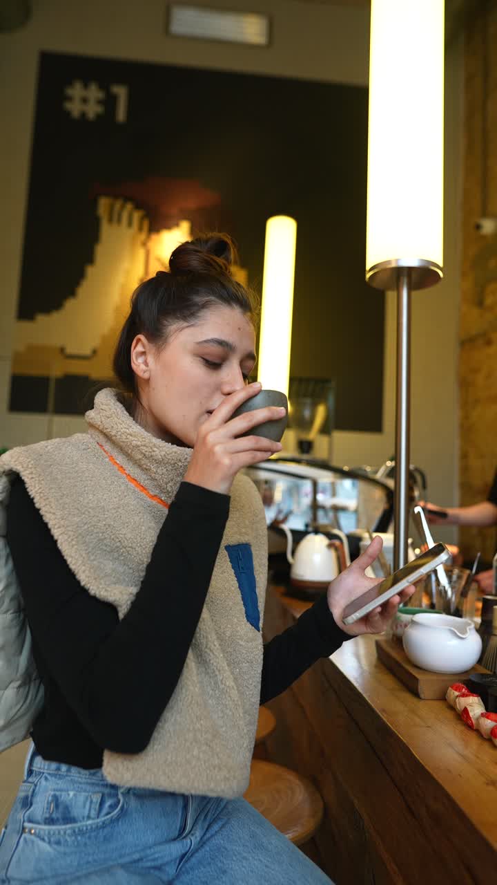 Giovane donna che si gode una bevanda in un caffè.