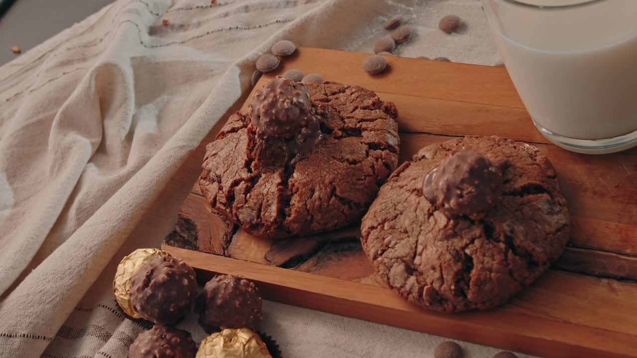 Biscotti al cioccolato con tartufi di cioccolato e un bicchiere di latte sul tavolo.