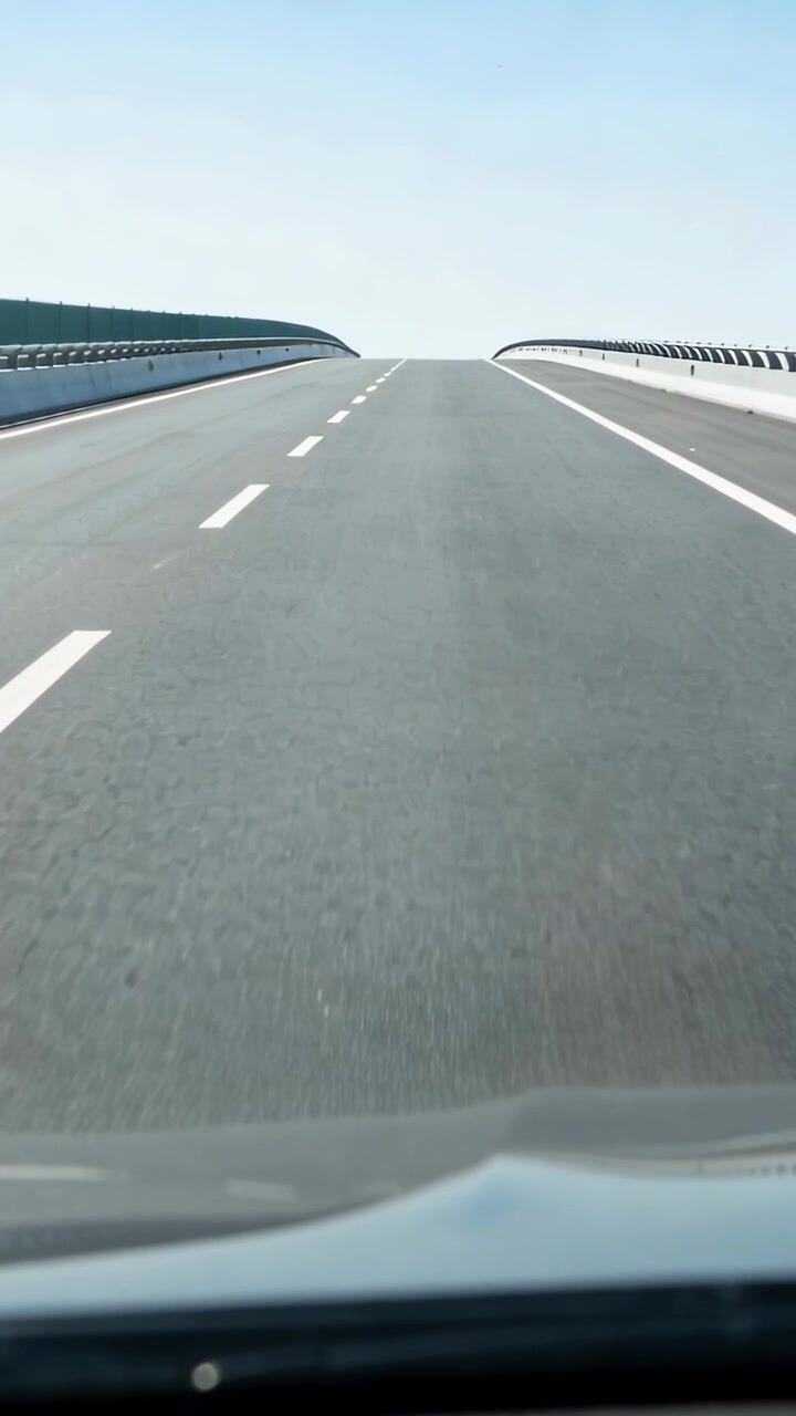 Vertical video: Driving car forward along sunlit country lane toward crest, showing windshield dirt