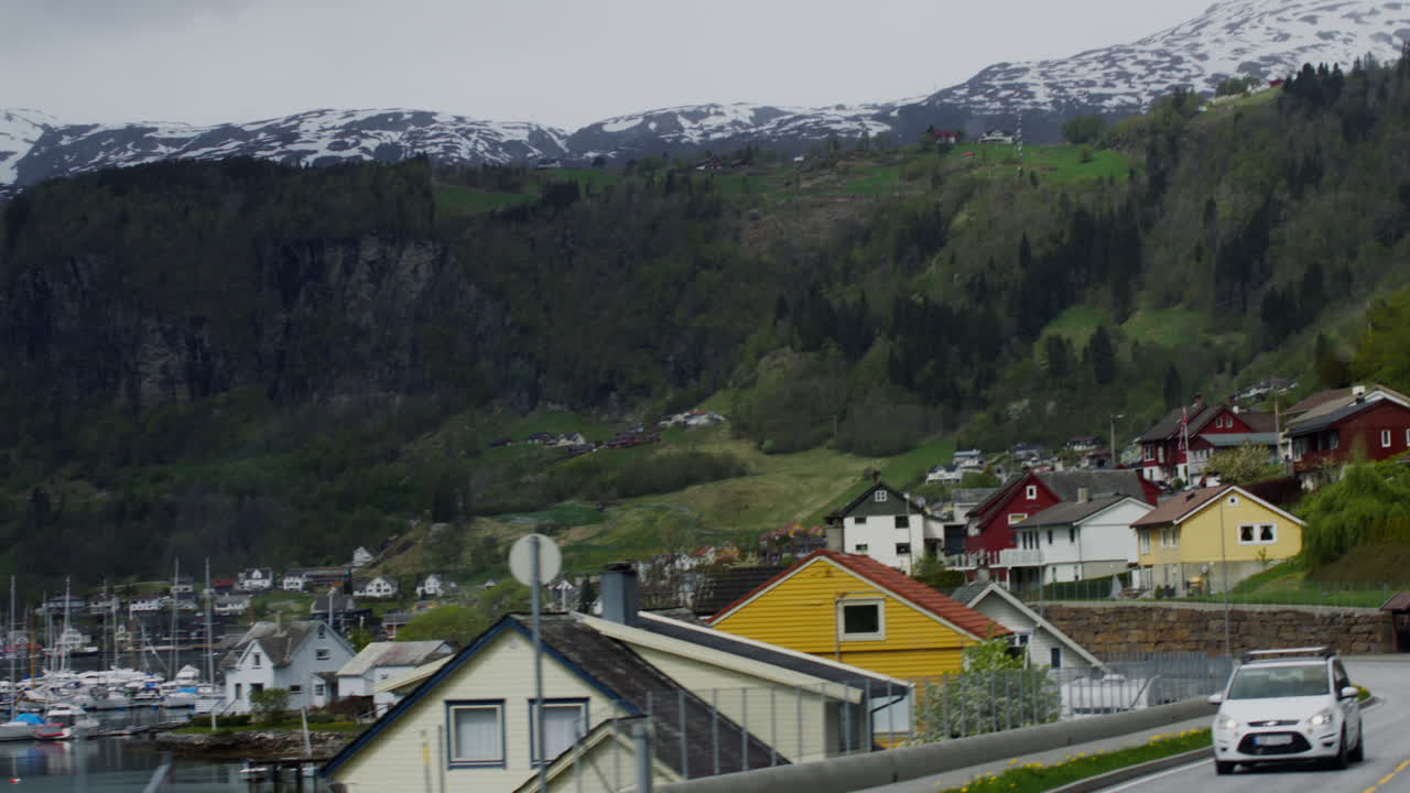 dolly disparado hacia casas brillantes con barcos en el puerto rodeado por montañas cubiertas de nieve