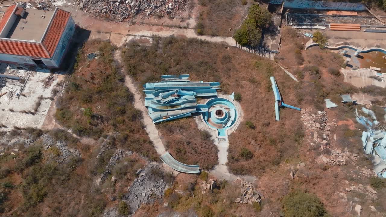 broken down water slide pieces in abandoned park, Aerial rotating bird's eye view