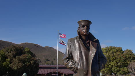 san francisco, california - el monumento al marinero solitario con las banderas de estados unidos y california expuestas en el fondo - de cerca