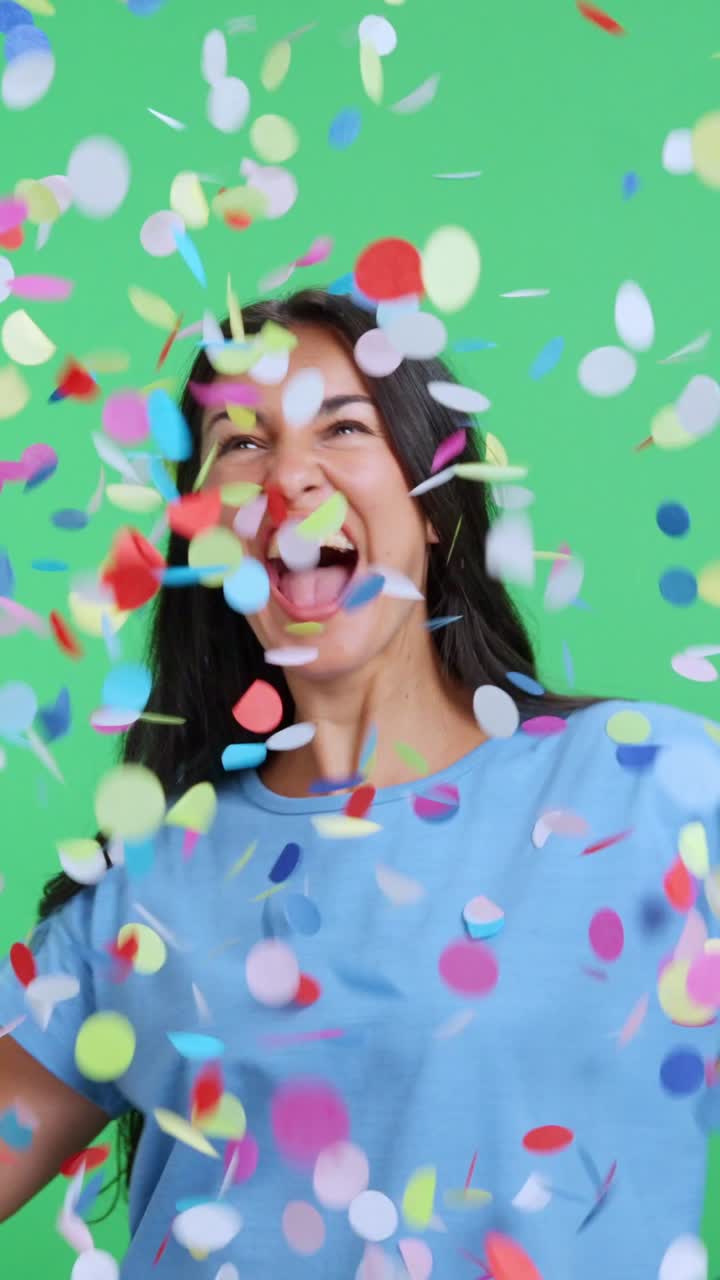 Donna felice e sorridente che lancia coriandoli colorati.