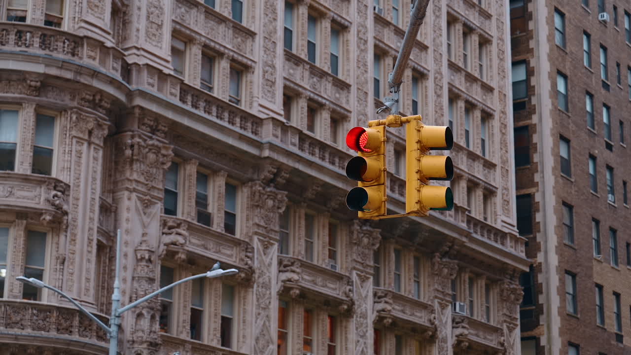 Street light with red on hanging over the road. Stunning historical architectural design of the high-rise building at backdrop. New York, United States
