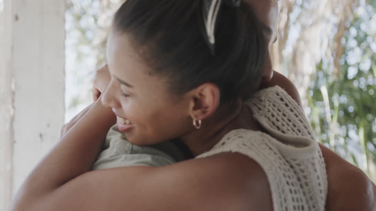 다양한 행복한 커플이 슬로우 모션으로  ⁇ 빛이 넘치는 해변집 베란다에서 미소 짓고 포옹하고 있습니다.