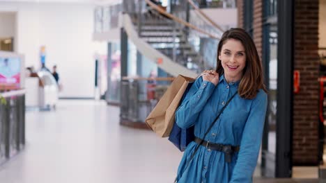 mujer girando con bolsas de compras en el centro comercial