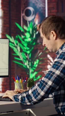 Vertical video Man at home looking at UI on PC screen, typing and executing programming code