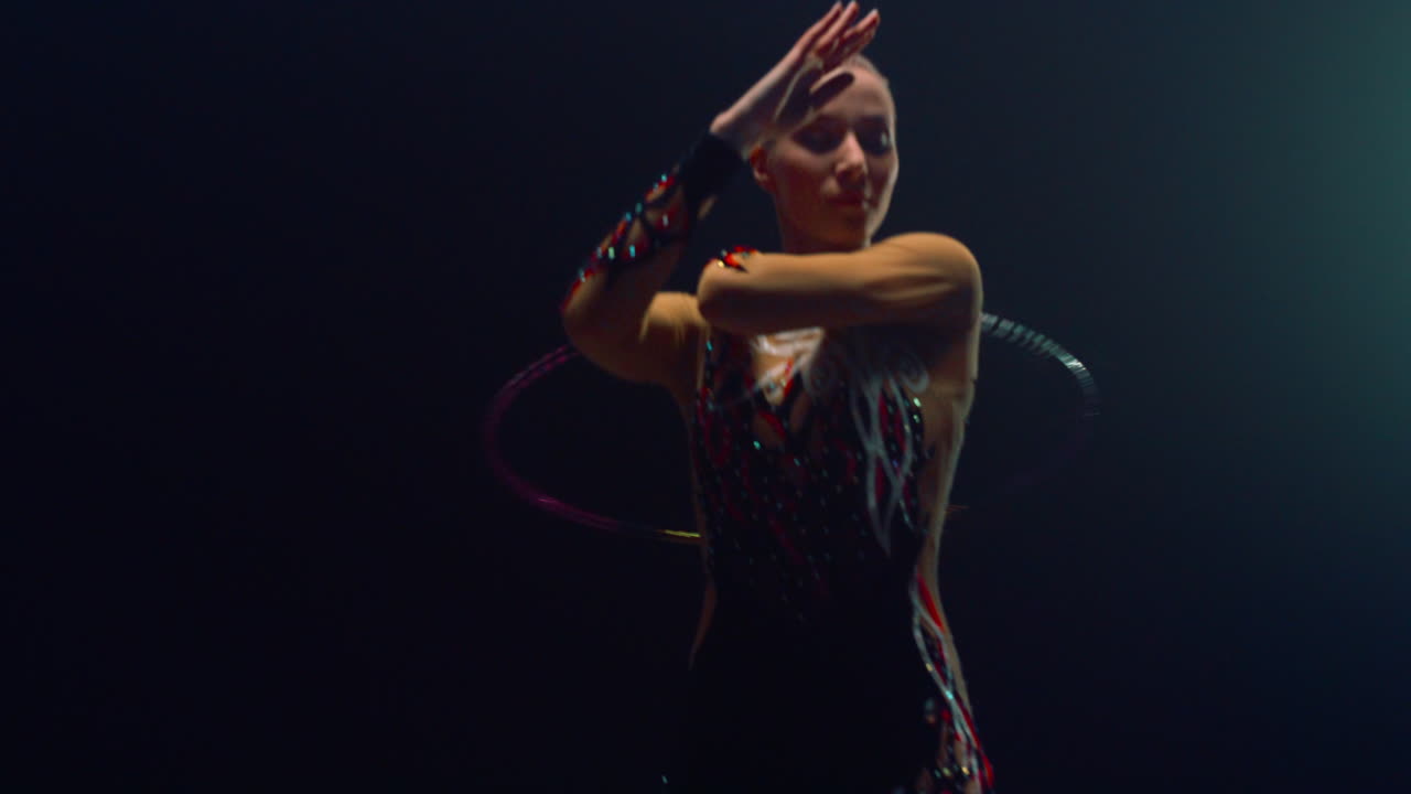 Slim woman looking camera during performance hula hoop. Girl doing gymnastics