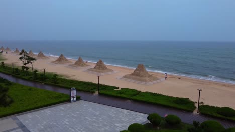 Cinematic natural beach with seaside promenade green graden park, sand sculptures, blue sky and sea