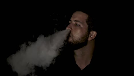 man smoking smoke from his nose on black background, slow motion