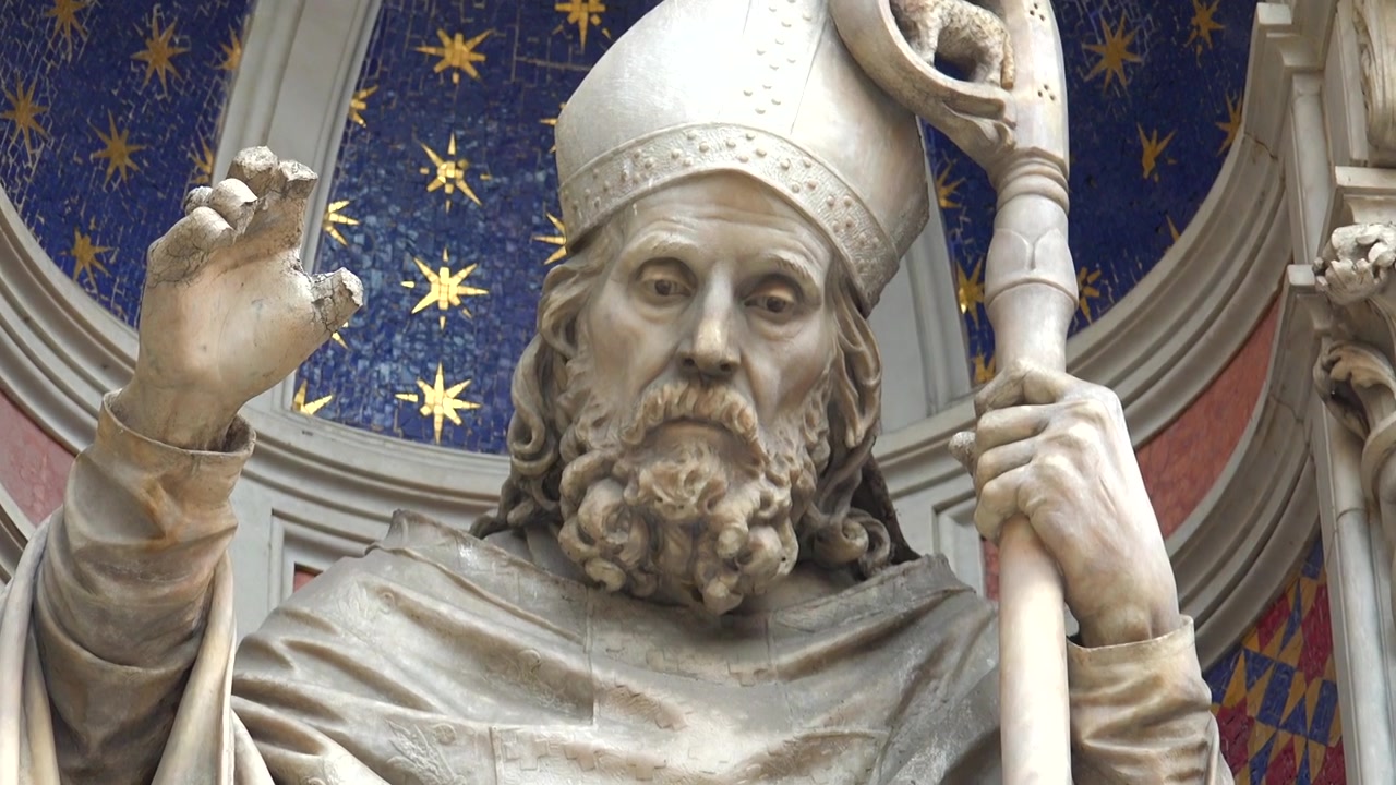 Detailní záběr kamenné sochy biskupa na fasádě florentské katedrály.