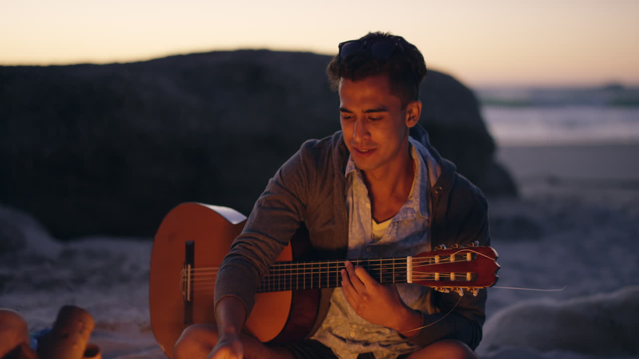 해가 지는 해변에서 기타를 연주하는 친구들