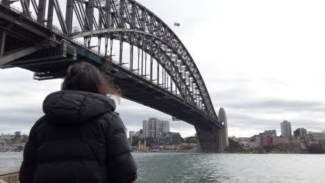 woman looking at sydney harbour bridge from dawes point reserve in sydney, nsw, australia