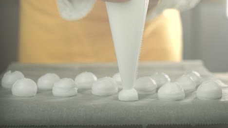 vegan chef places whipped egg white cream with a icing bag on a backing plate to make meringue