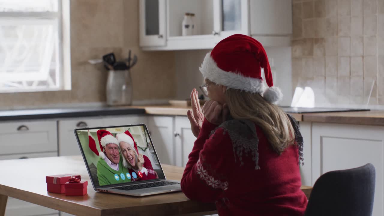 mujer caucásica con sombrero de papá noel en una videochat portátil durante la navidad en casa