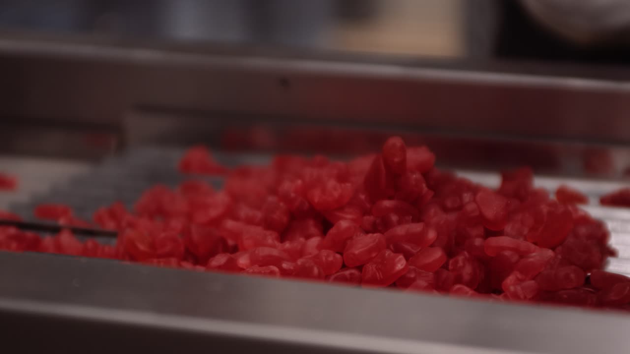 분류를 위해 기계에 떨어뜨린 빨간색 젤리 구미 비타민 - 기능성 식품