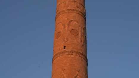 the camera scans the minaret of the mardin ulu mosque, made of cut stone