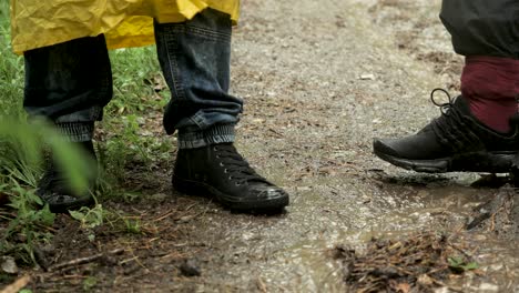 people walking in a muddy forest path during a rainy day