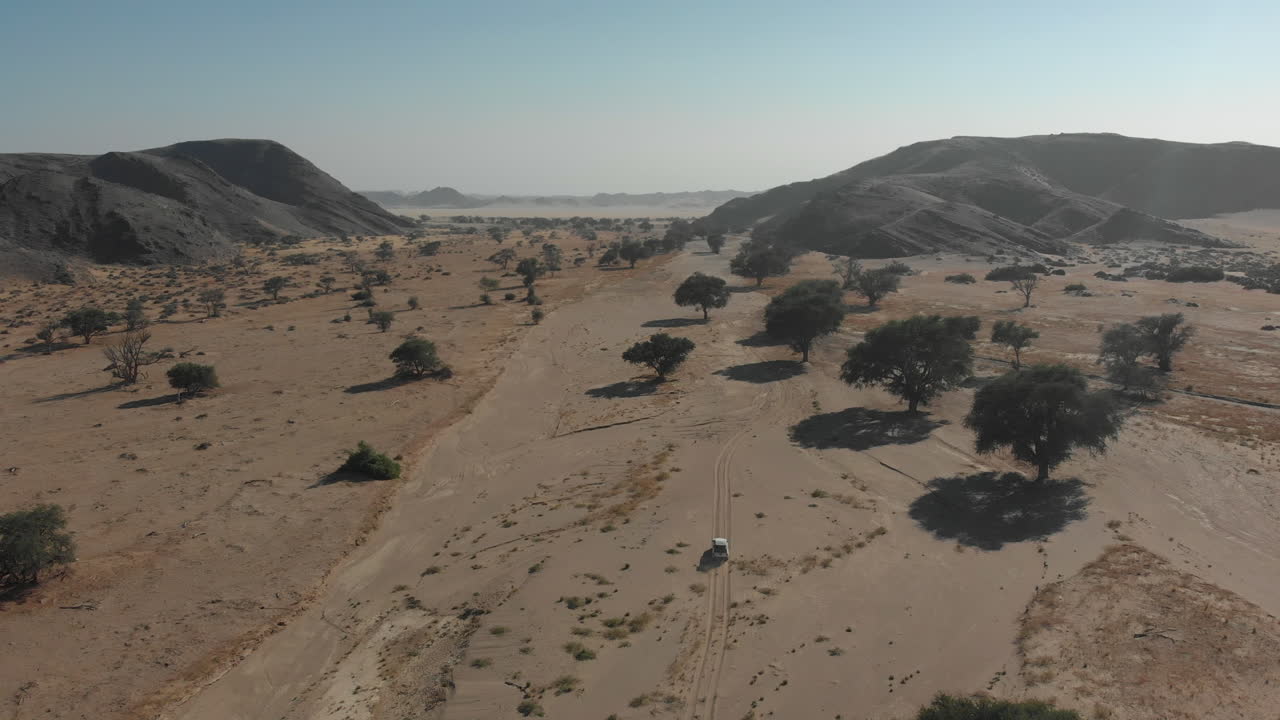 toma aérea lejana tras la conducción del vehículo en el lecho seco del río desierto africano