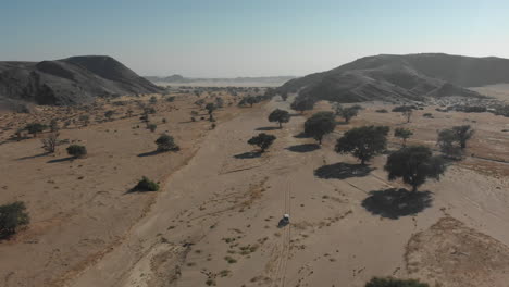 Toma-Aérea-Lejana-Tras-La-Conducción-Del-Vehículo-En-El-Lecho-Seco-Del-Río-Desierto-Africano