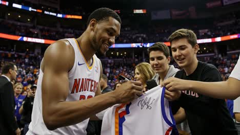 exciting moment as basketball player signs autographs for fans after the game, showcasing the connection between athletes and their supporters in sports culture