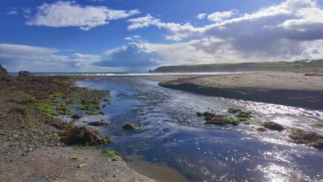 Irland:-Epische-Orte-Im-Zeitraffer:-Der-Fluss-Mahon-Mündet-Am-Strand-Von-Bunmahon-Ins-Meer,-Die-Küste-Von-Waterford-An-Einem-Sommerabend-Mit-über-Das-Meer-Ziehenden-Regenwolken