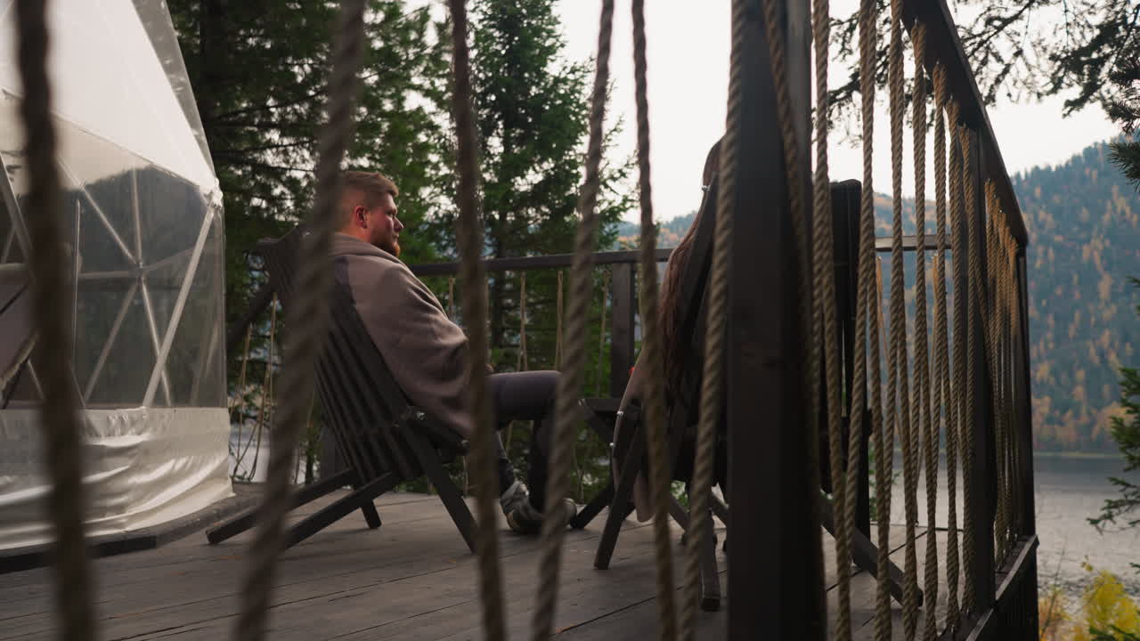 una pareja relajándose en una cubierta junto al lago.