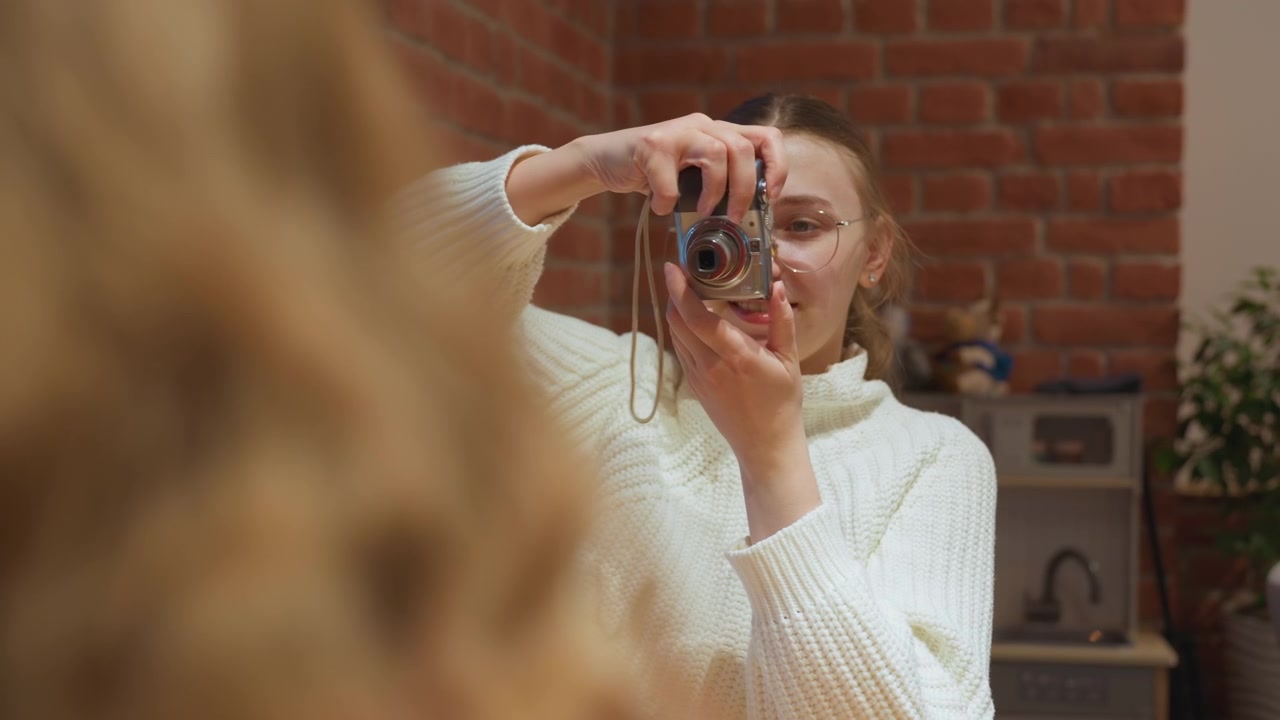Giovane donna felice che scatta una foto con una fotocamera digitale