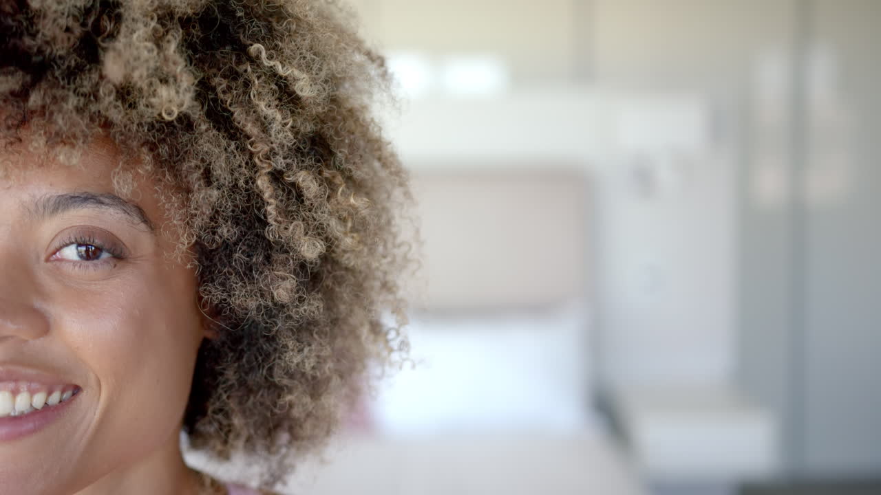 Donna sorridente con i capelli ricci a casa, primo piano del viso e dell'occhio, con spazio per il testo