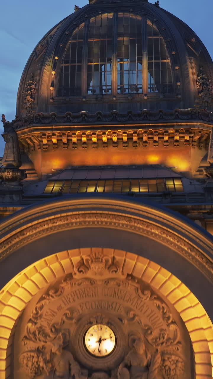 Vertical aerial drone view of the illuminated Palace of the Deposits and Consignments in the evening. Blue hour in Bucharest, Romania