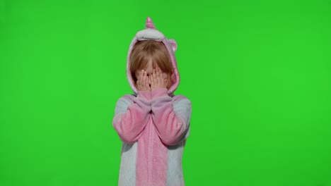 little blonde child in unicorn costume crying, wiping tears with her hands on chroma key background