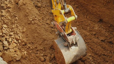 large digger bucket extracts soil from trench