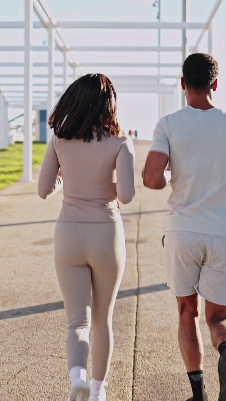 Giovane coppia che fa jogging insieme su un sentiero soleggiato all'aperto