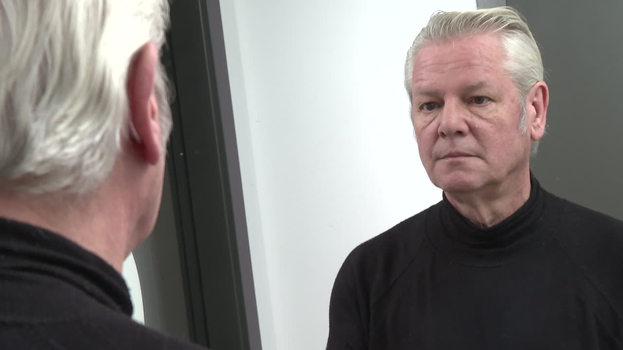 hombre aplicando crema facial frente al espejo