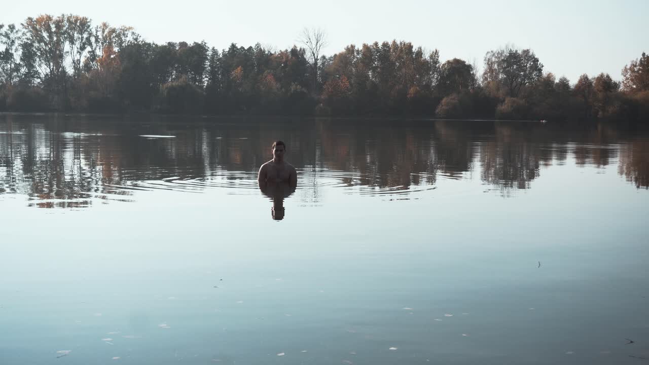 un joven en forma relajándose en el agua fría y colorida del enorme lago
