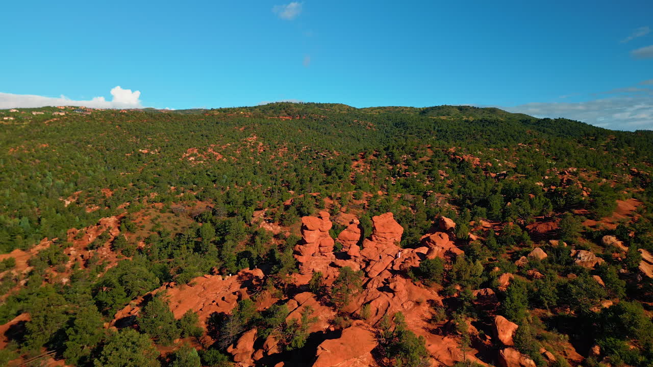 Approaching red clay rounded rocks lit with sun. Vegetation covers the scenery of Capitol Reef National Park, Utah, United States