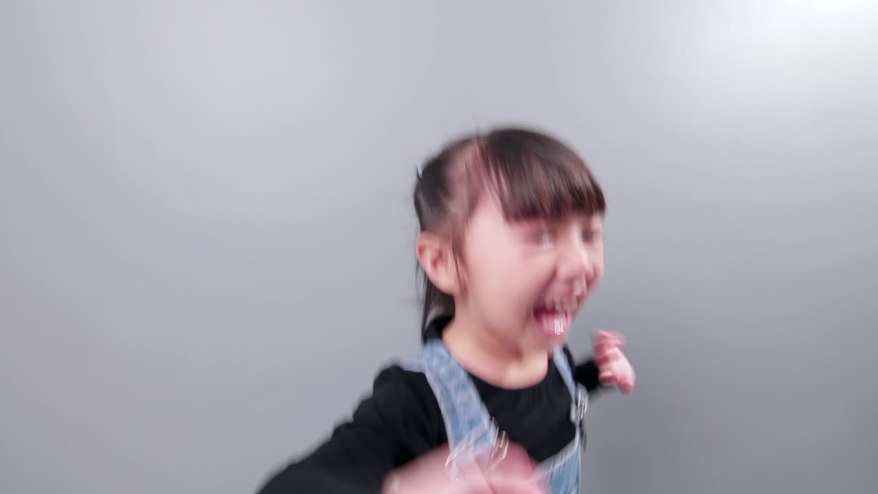 Little Asian girl enjoy using smartphone for video call, smiling and jumping with happiness