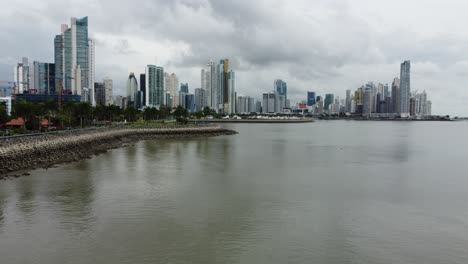 Reversa-Aérea-A-Lo-Largo-Del-Sendero-Recreativo-Costero-Cinta-Costera-Con-Vistas-Espectaculares-Del-Horizonte-Del-Centro-De-La-Ciudad-De-Panamá.