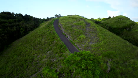 woman rides scooter up lush teletubbies hills, nusa penida, indonesia