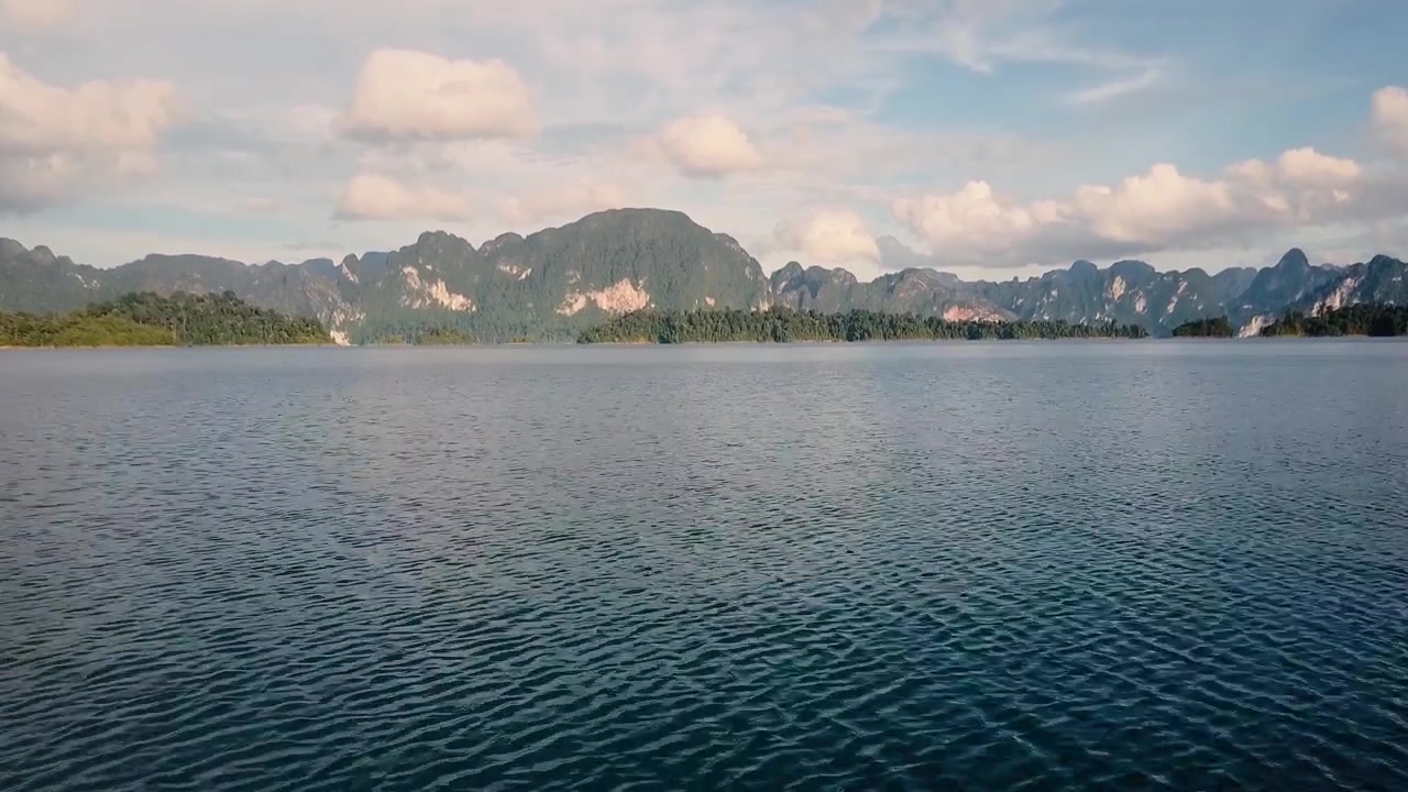 ฟุตเทจโดรนคุณภาพสูงบินร่อนเหนือทะเลสาบเขตร้อนและลอยขึ้นสู่ทิวทัศน์ภูเขาที่สวยงามในประเทศไทย น้ำนิ่งสงบ ทิวทัศน์ป่า และการเคลื่อนไหวทางอากาศแบบภาพยนตร์ที่มองจากมุมสูง
