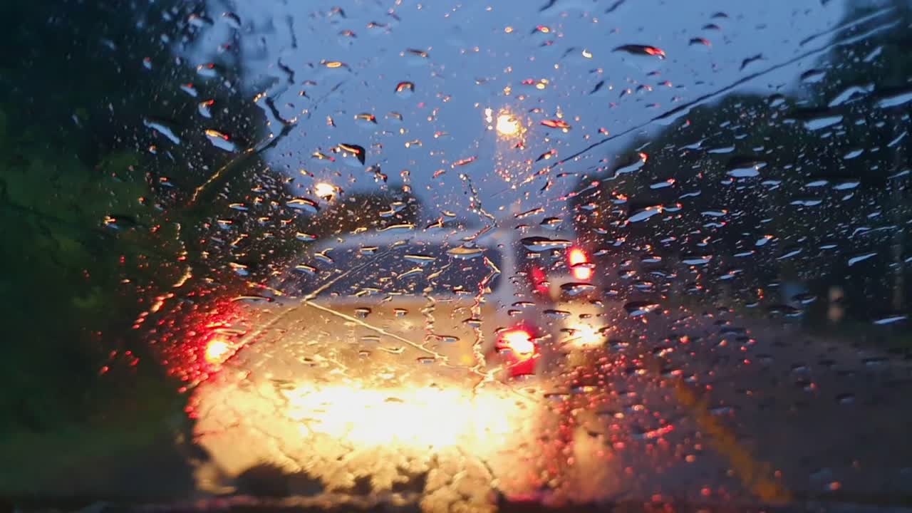 Raindrops Flow Down the Glass of a Car while we are in traffic
