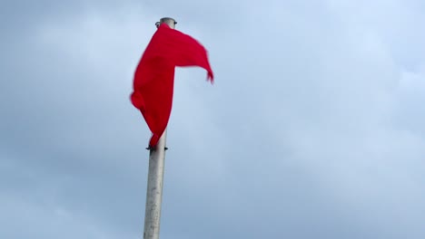 A-red-flag-flies-in-the-wind-indicating-dangerous-surf-at-the-beach-in-Florida