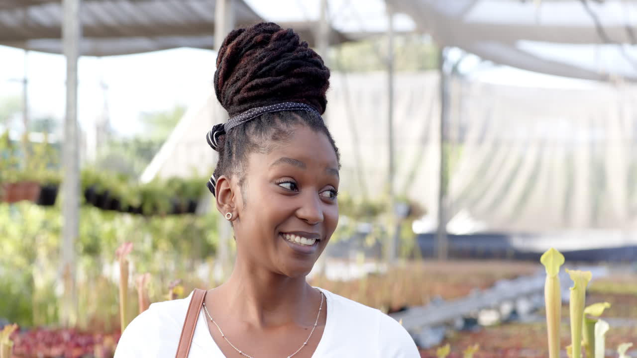 Smiling woman enjoying plant nursery, surrounded by vibrant greenery, in greenhouse, copy space