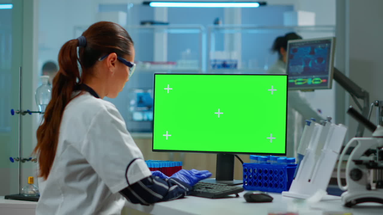 investigadora escribiendo en una computadora con una pantalla verde