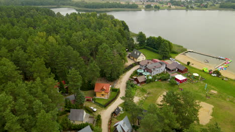 aerial view of green forest, cabin, beach, and lake in hartowiec, poland