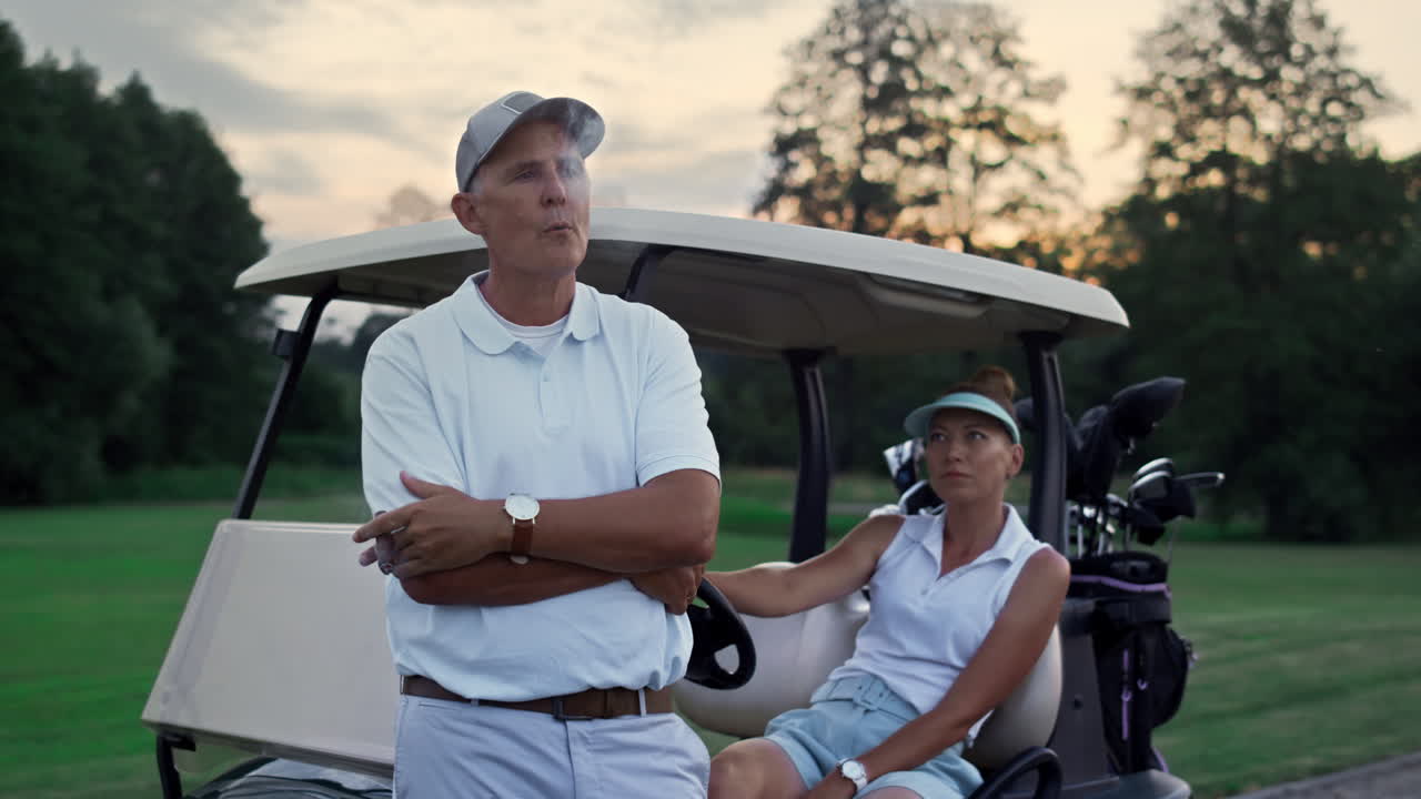 부유한 부부는 페어웨이에서 골프 저녁을 즐기고, 가족 골퍼들은 여름 휴가를 휴식합니다.